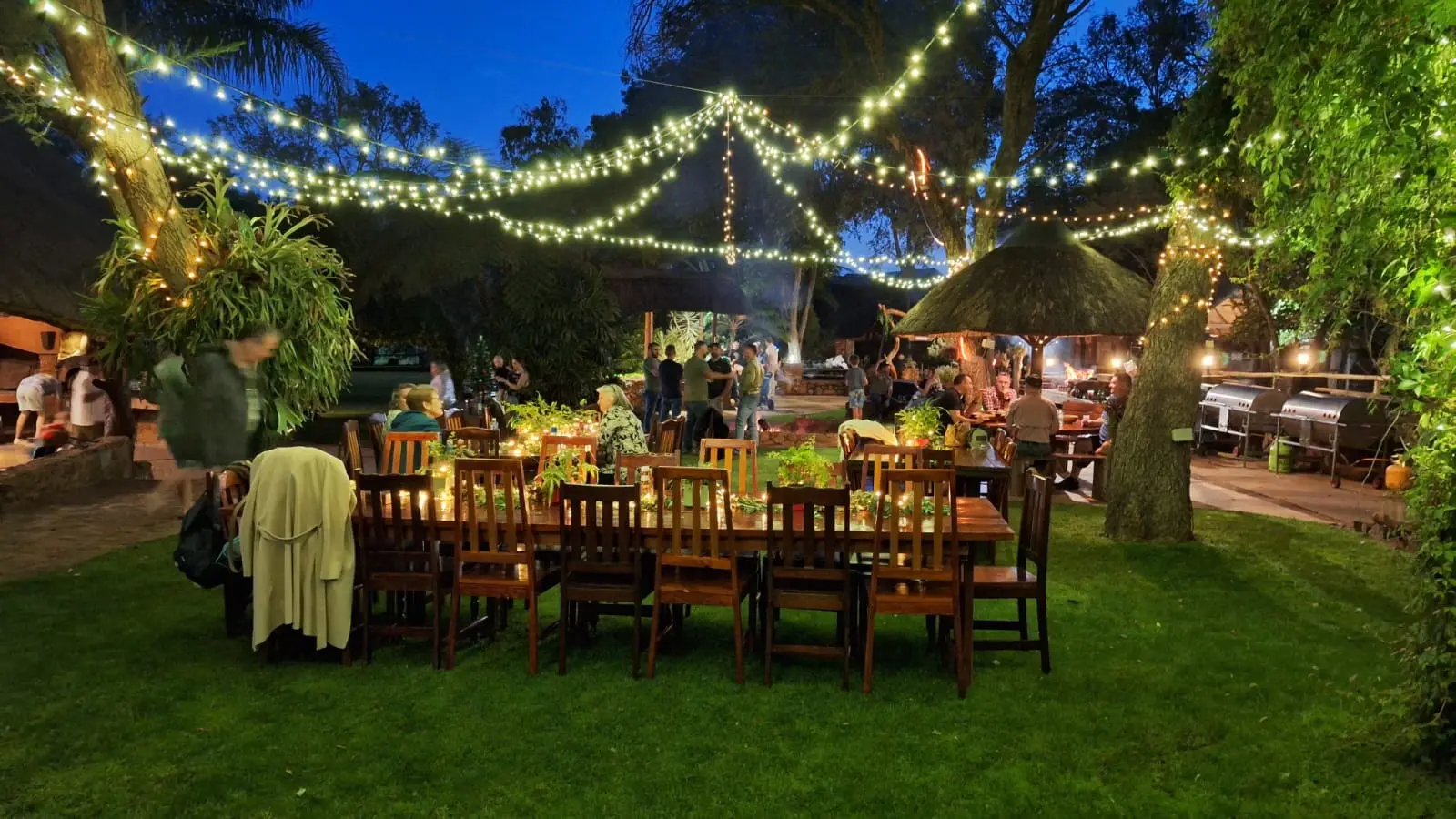 Long tables under fairy lights in the garden at dusk
