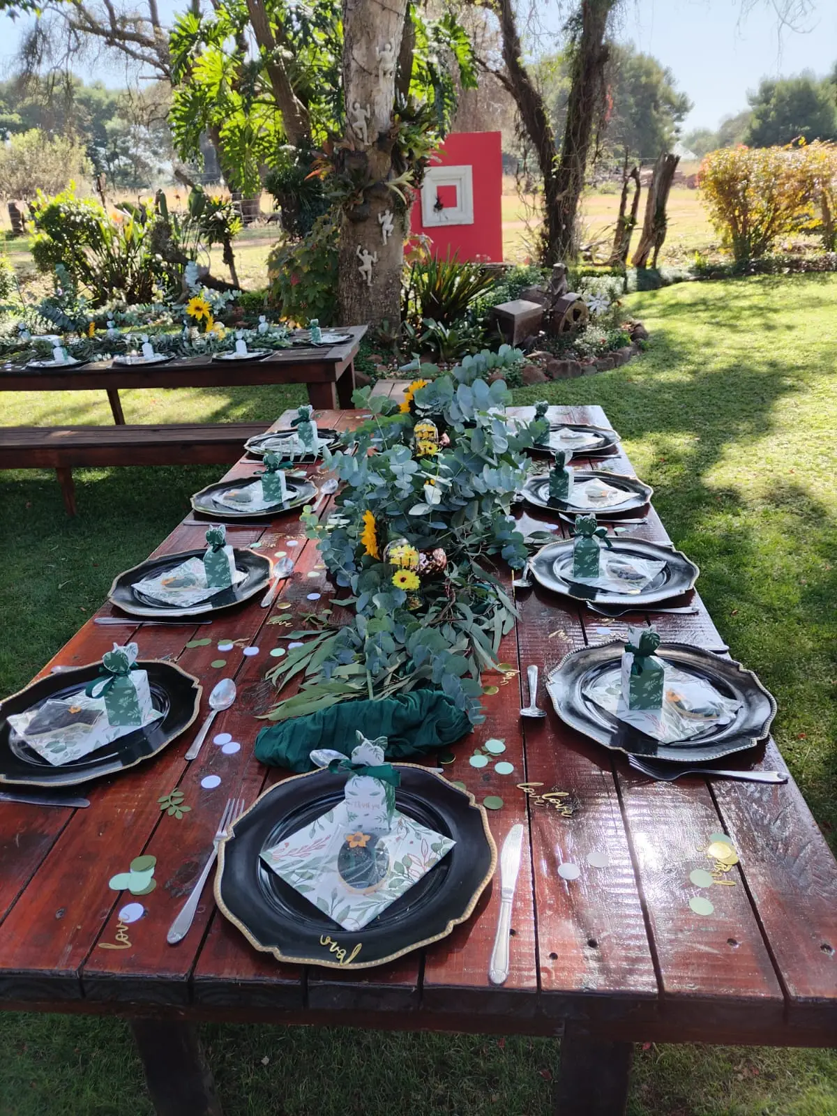 A long table dressed with greenery under the trees